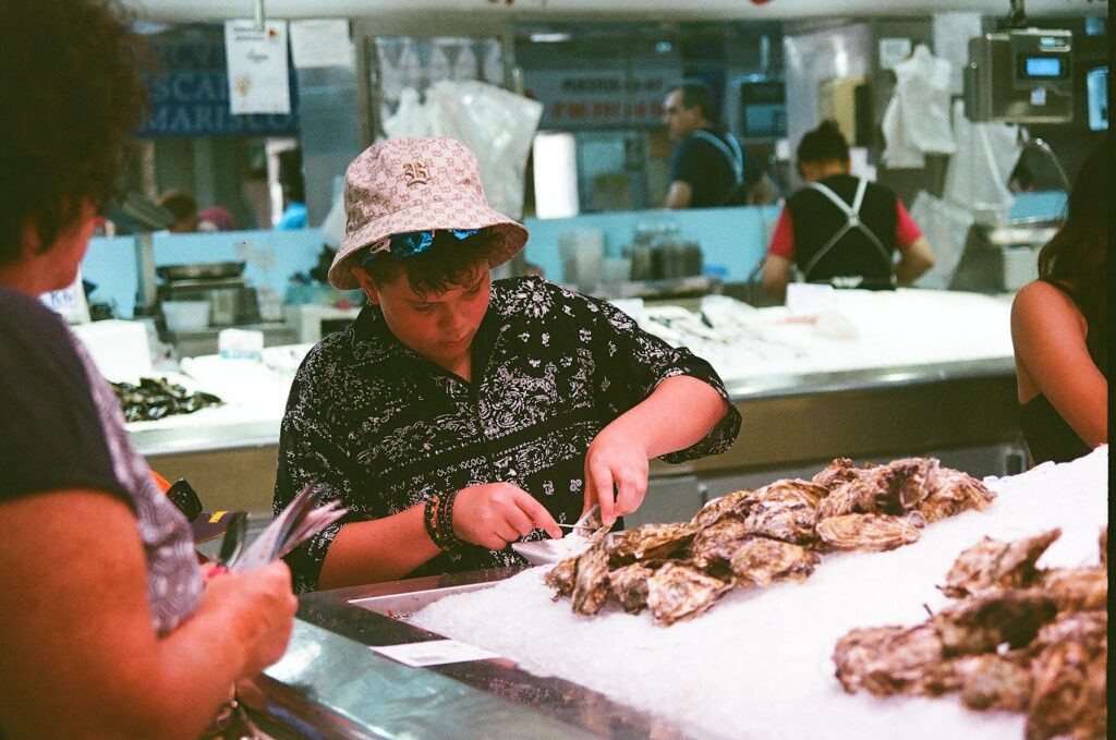 About A woman in a sun hat cleaning fresh fish at a market counter