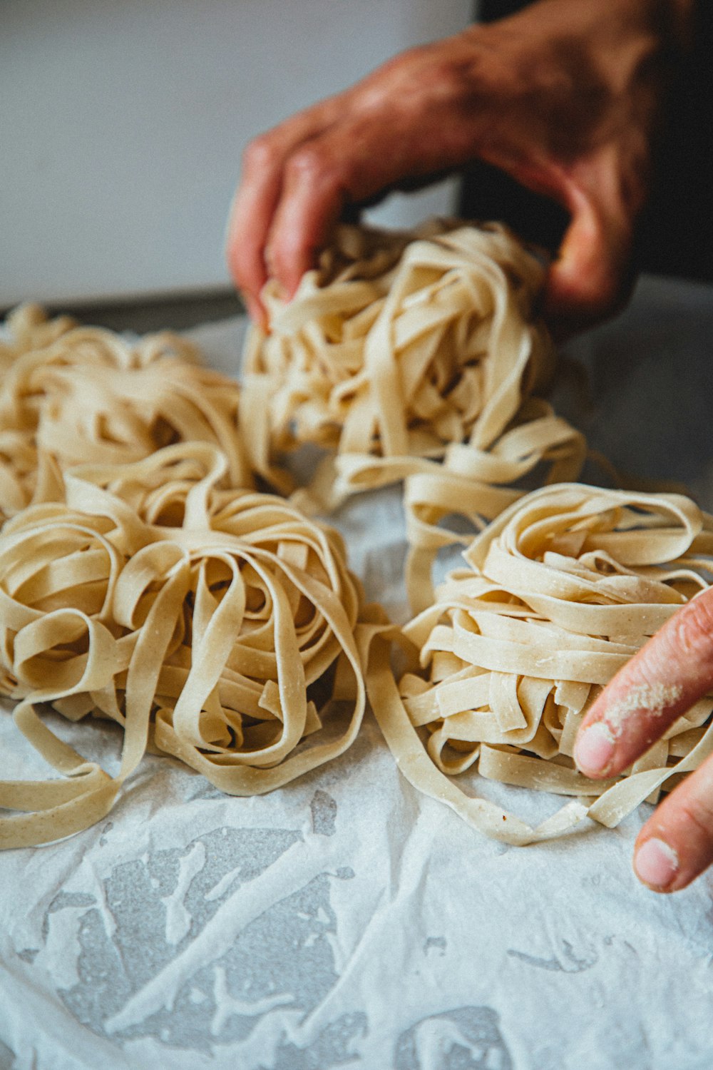 Home Hands shaping nests of fresh handmade tagliatelle