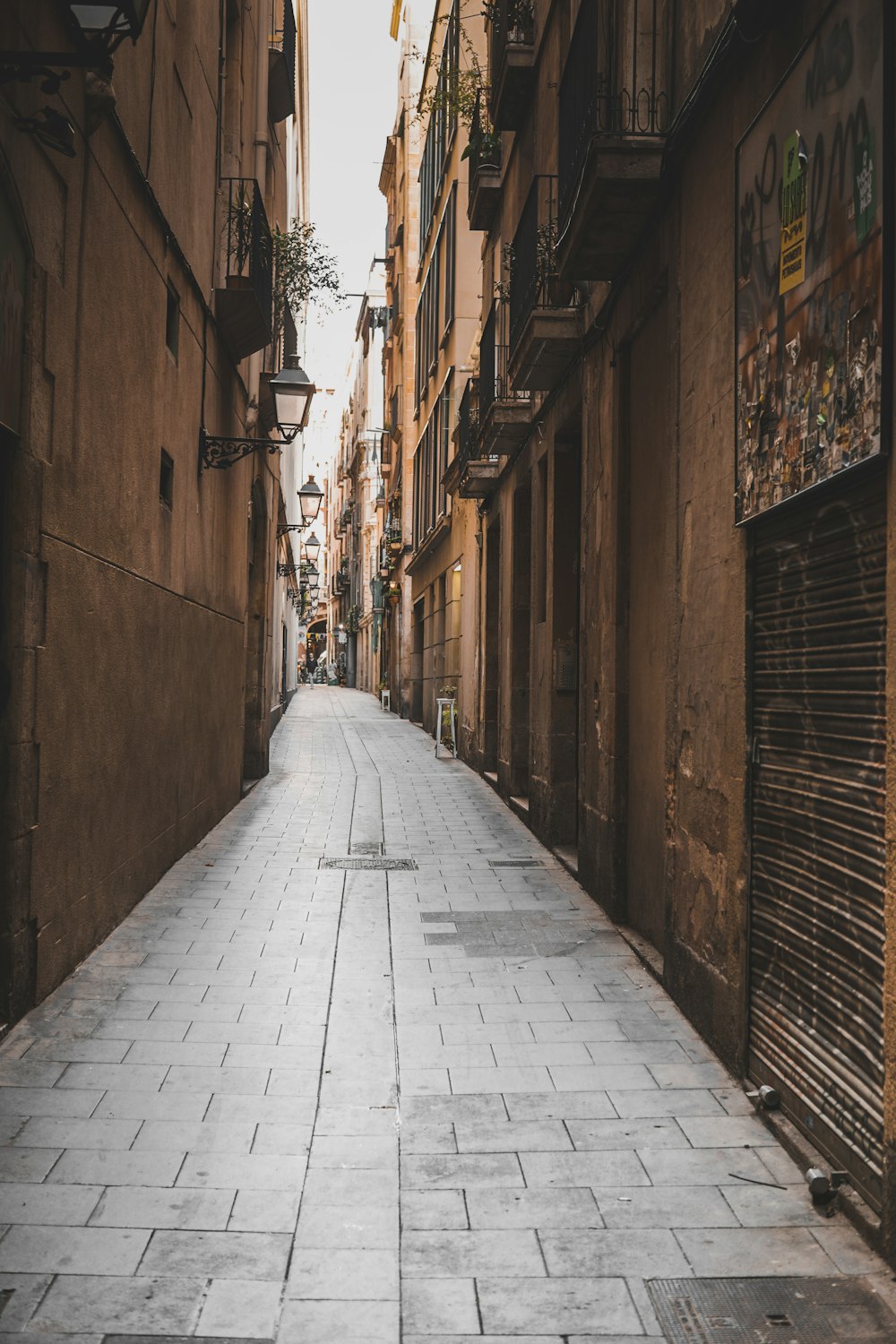 Home A narrow paved street between old stone buildings with wrought-iron balconies